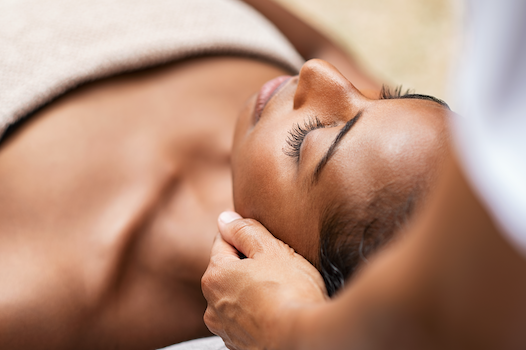 woman laying on the bed receiving a facial treatment from an esthetician
